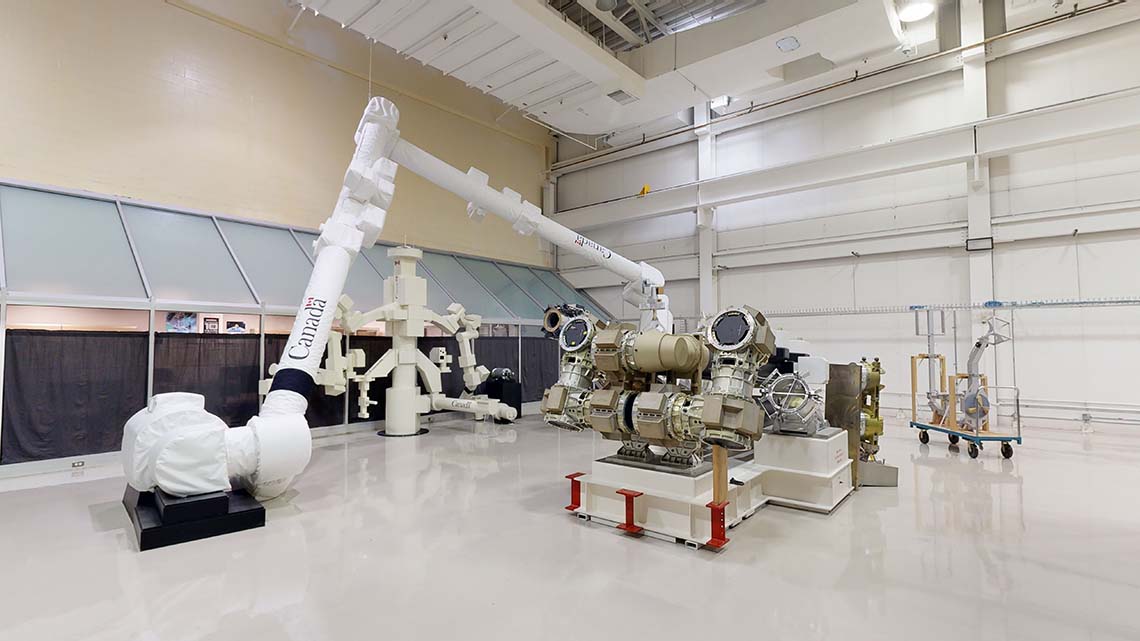 Une salle à haut plafond avec quelques grands modèles, dont le Canadarm2 et Dextre.