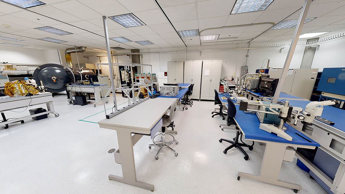 Laboratoire spacieux avec postes de travail bleus et équipements scientifiques.