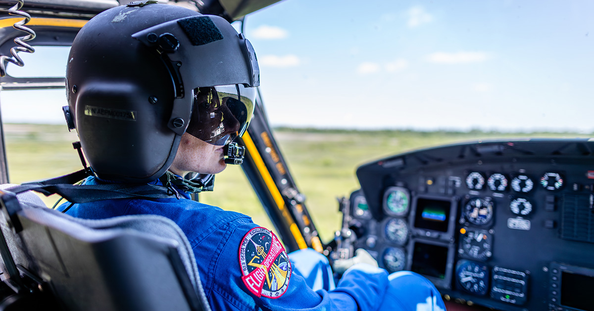 Jenni wears a helmet and flies helicopter