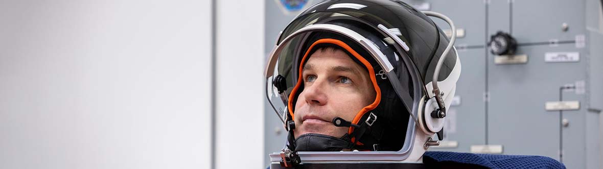 Jeremy sits wearing his spacesuit and helmet, the Canada flag on his left shoulder.