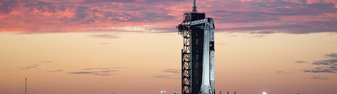 A rocket sits on a launch pad at sunset.