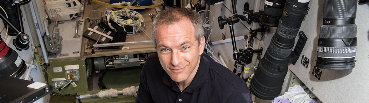 David holds a test tube shaped bubble detector, with a screen in front of him.