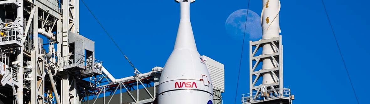 The full Moon shines behind the SLS rocket.