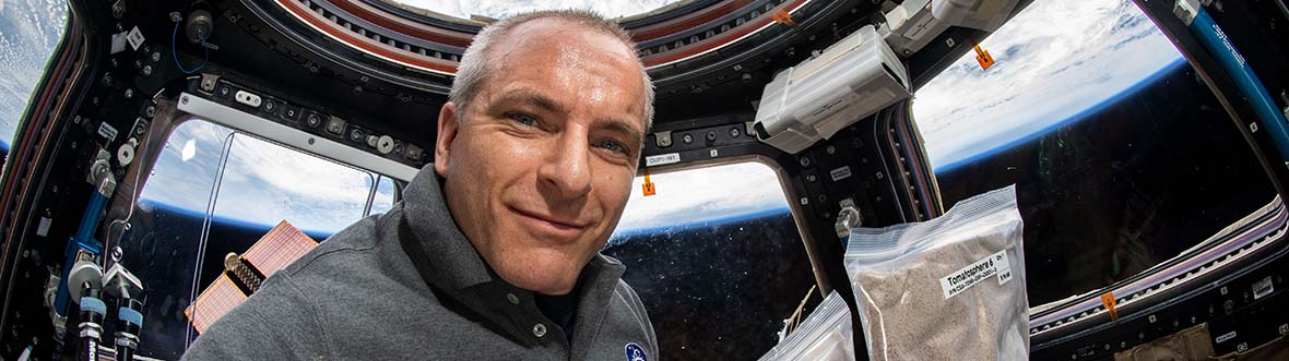 Astronaut David Saint-Jacques holds two Ziploc bags full of tomato seeds.