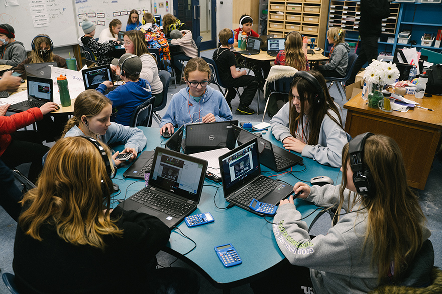 Teams of students sit around tables to simulate a lunar mission and remotely operate a rover using laptop computers