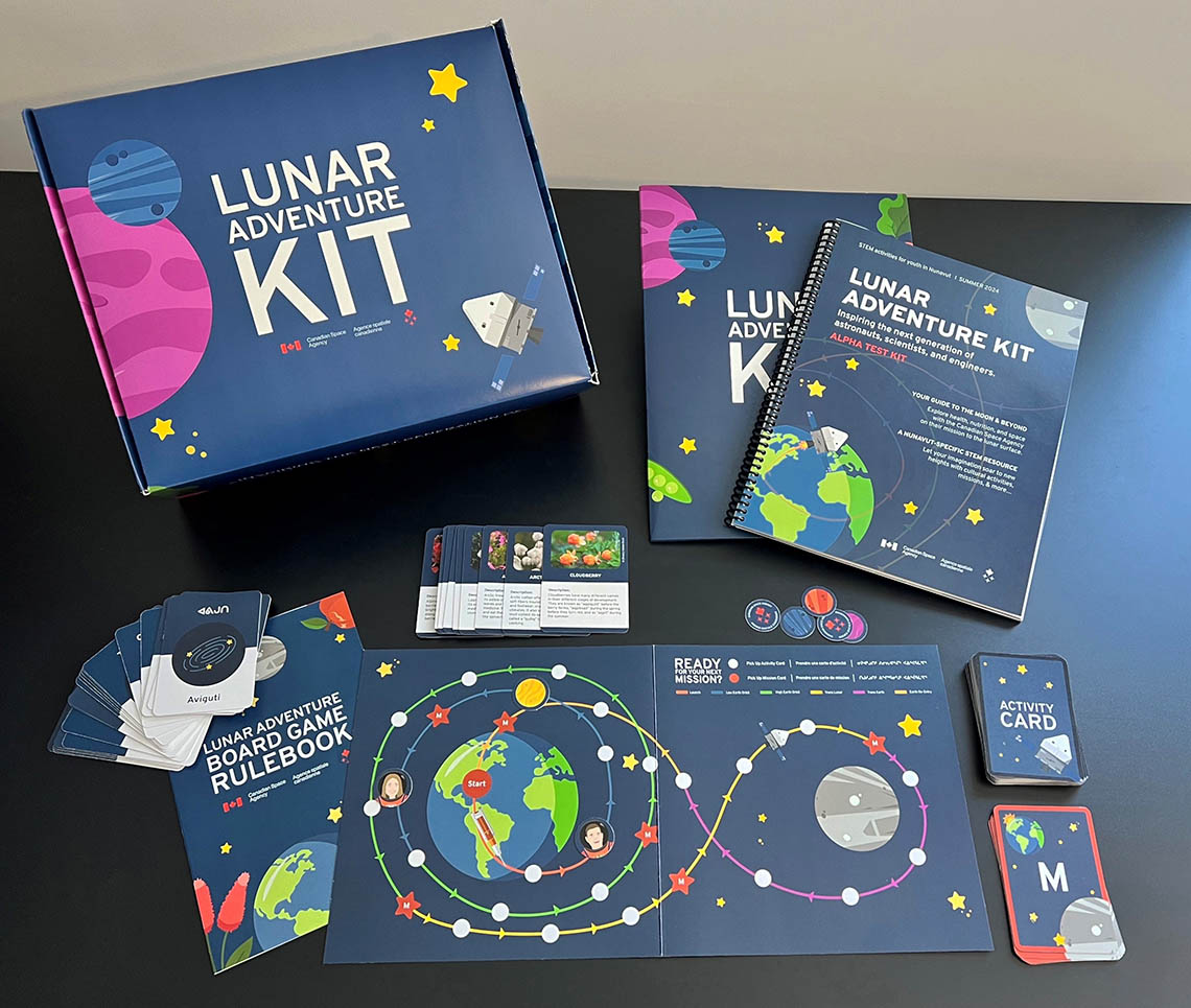 A box with “Lunar Adventure Kit” on the cover, with leaflets and playing cards spread out around it.