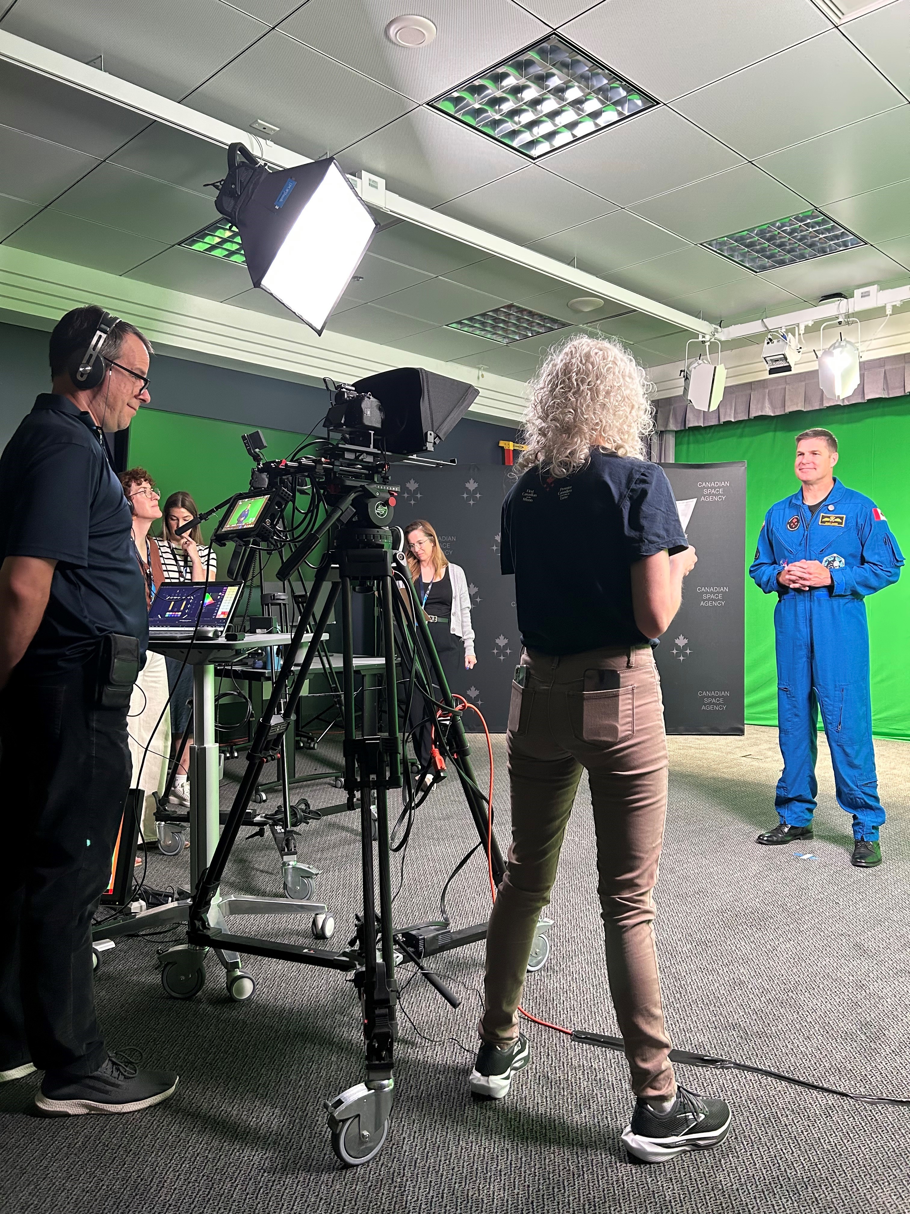 Jeremy in front of a green screen with a group of people filming him.