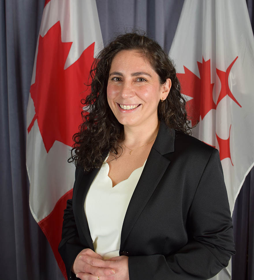 Kristen poses in front of the Canada and CSA flags.