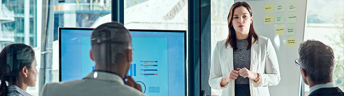 Jenni Gibbons in a blue flight suit speaks at a podium