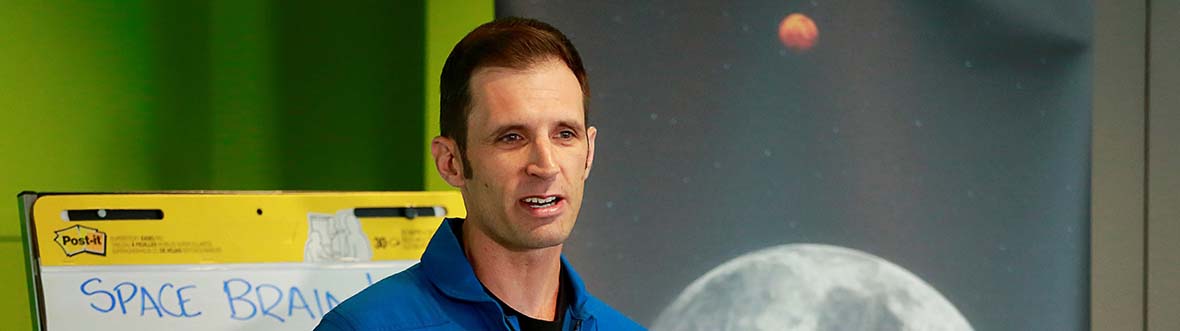 Josh speaks next to a banner of the Moon.
