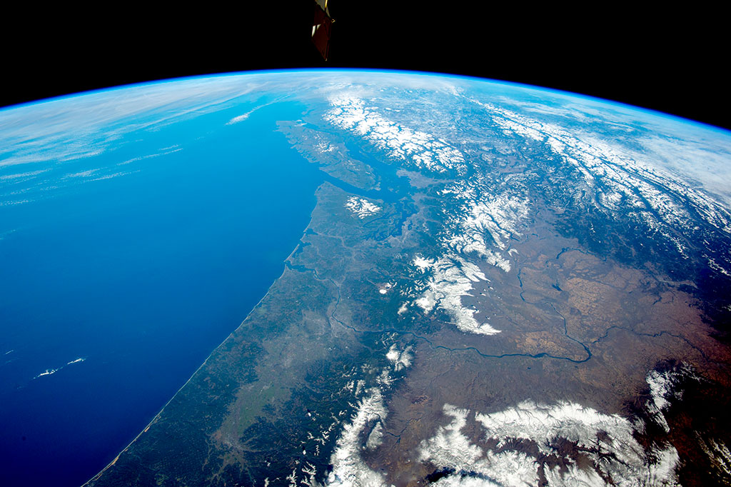 The snow-covered Cascade Range in the northwest United States in the foreground gives way to the Rocky Mountains and Coast Mountains in Canada, with Vancouver Island just offshore. Several active volcanoes—Mount St.Helens, Mount Rainier and Mount Hood—dot the Cascades in this photo taken by a crew member of the International Space Station. (Credit: NASA)