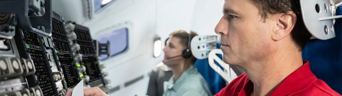 Deux hommes sont assis l'un à côté de l'autre devant un grand tableau de commande