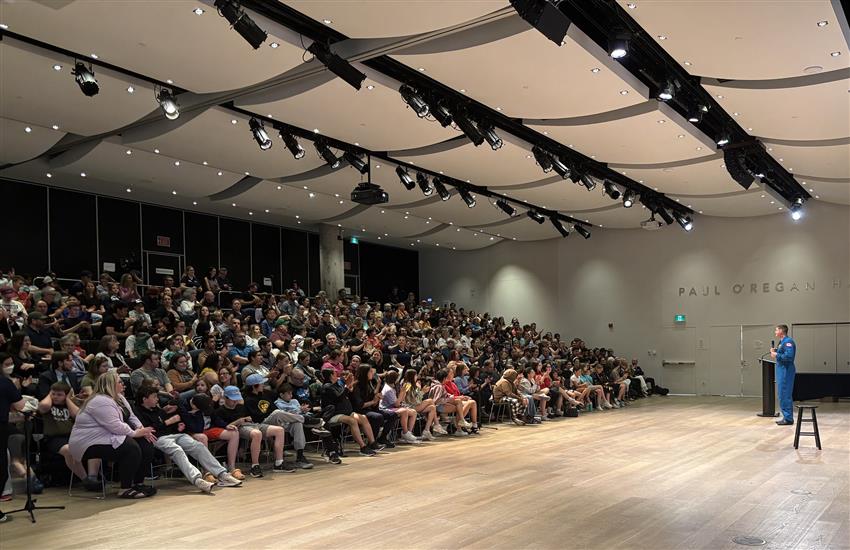 Jeremy, micro à la main, s'adresse à une salle comble.