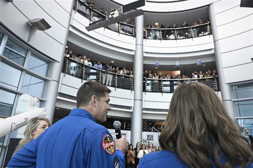 Jeremy speaks into a microphone in front of the employees.