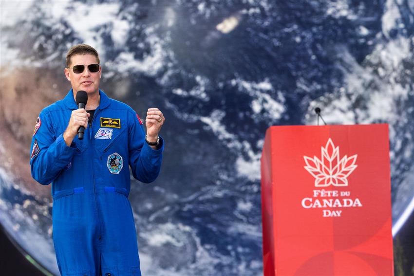 Jeremy au micro, près d'un lutrin avec les mots « Fête du Canada Day ».