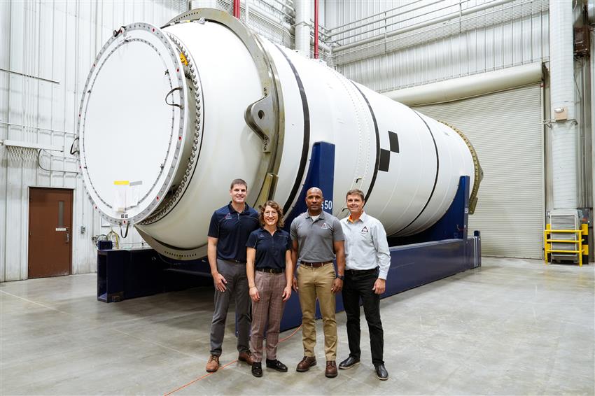 A group of people standing in front of a large cylindrical object.