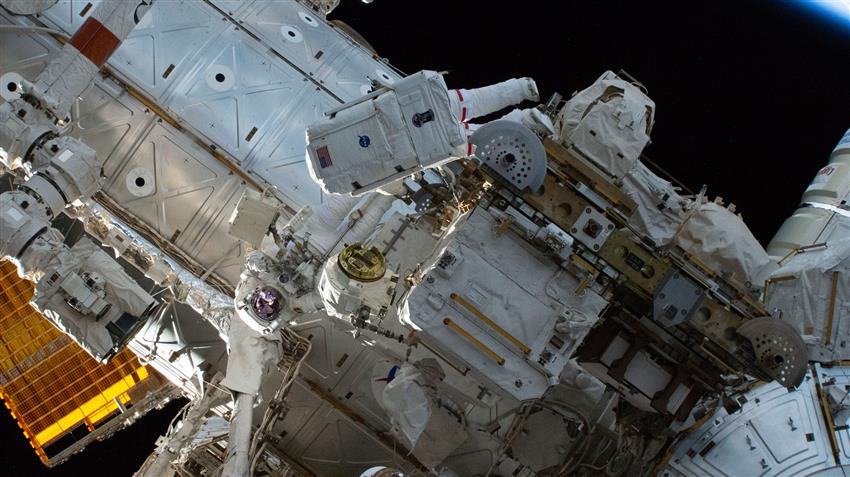 Jessica et Chris, en combinaison spatiale, sont à l'extérieur de la Station spatiale internationale. 