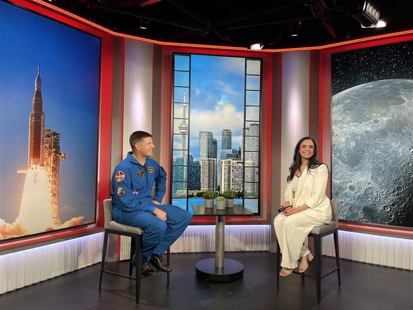 Jeremy et Arda sur des tabourets, devant des images d'une fusée, de Toronto et de la Lune.