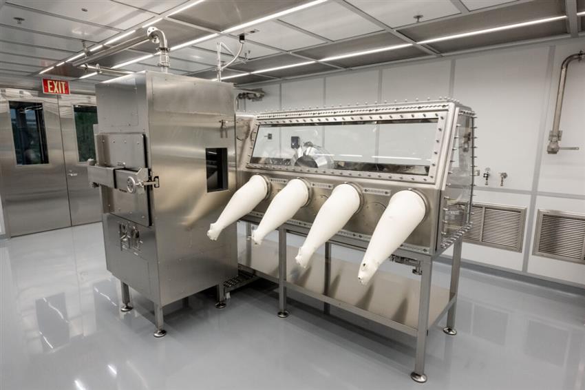 An empty cleanroom featuring a glove box from which four white gloves are hanging.