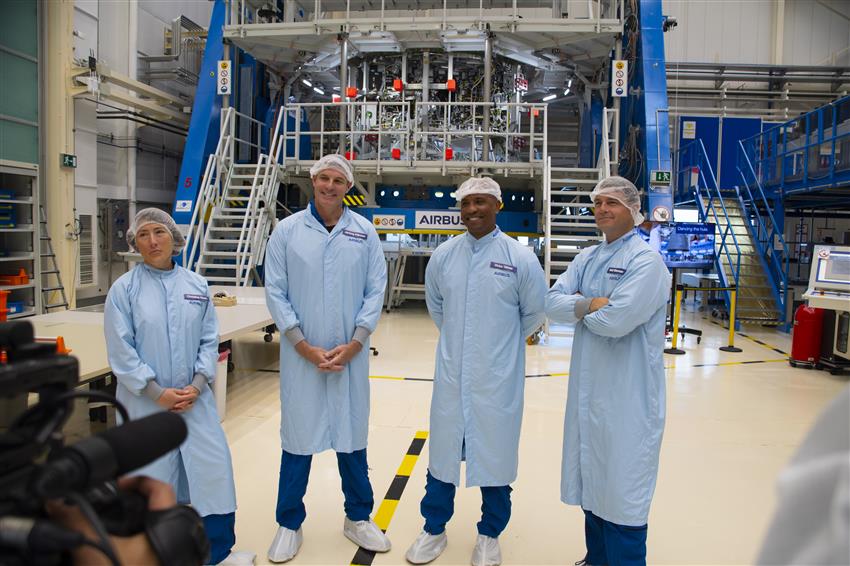 Four people wearing pale blue lab coats and head covers.