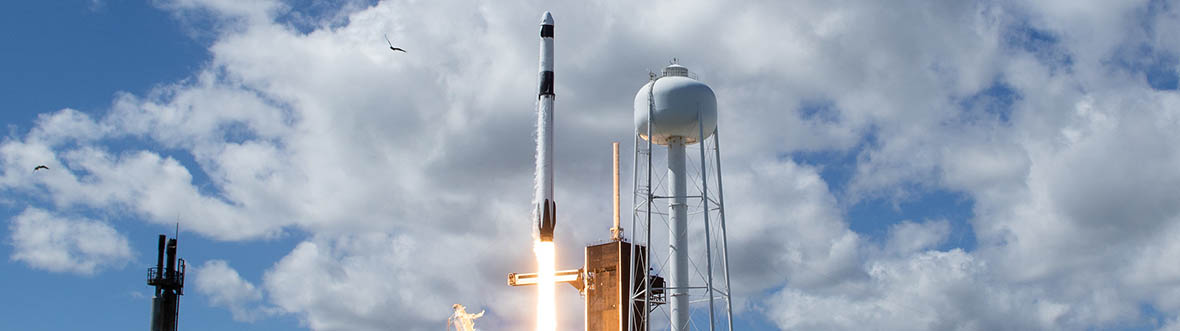 A rocket launches into a cloudy sky with flames and smoke visible at its base.